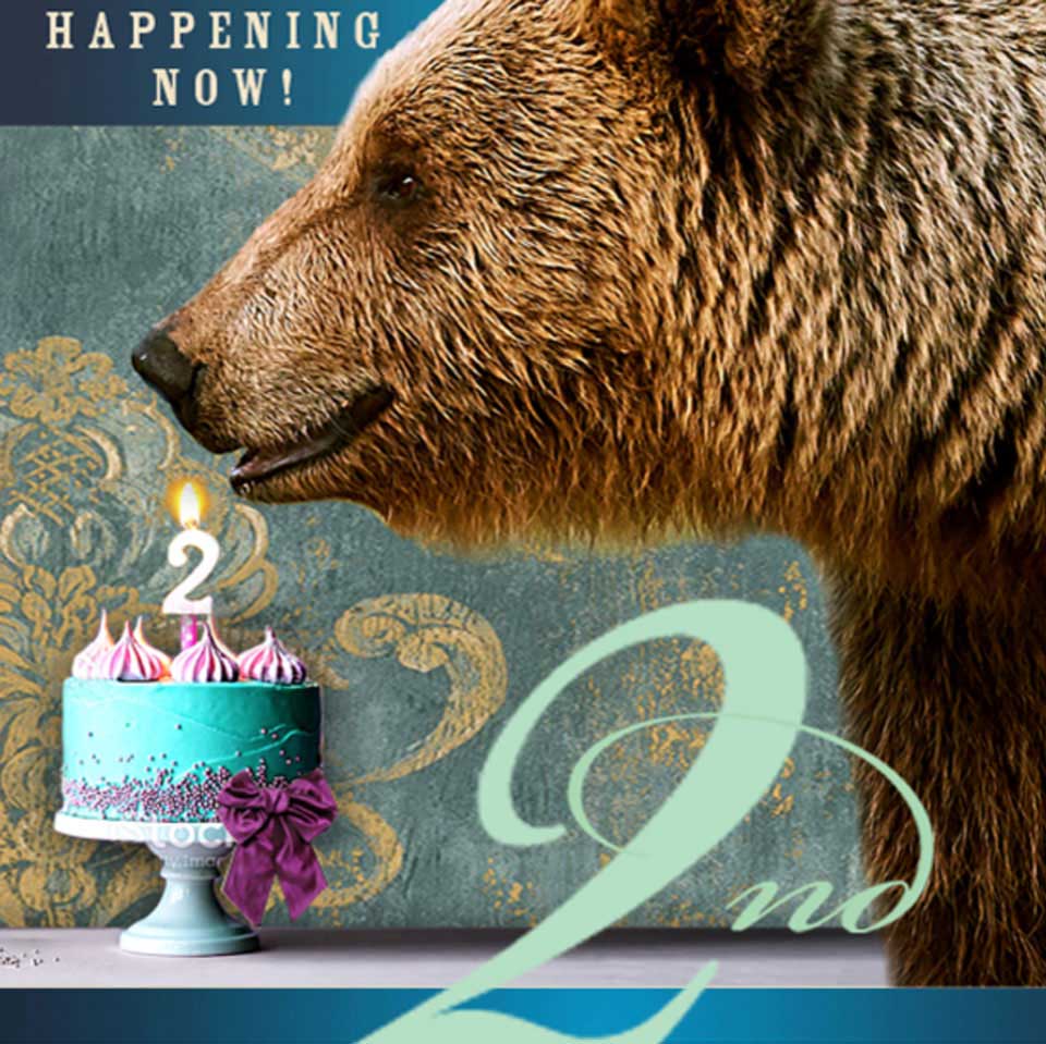 A Huge Bear Wines bottle stands near a lit candle on a blue cake with "2nd" written in large text. The phrase "Happening Now!" appears in the top left corner.